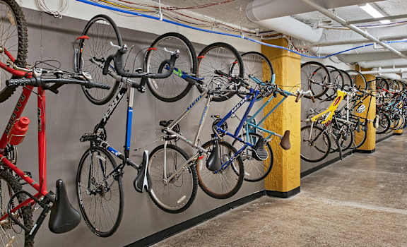 a large collection of bikes hangs on the wall in the bike room