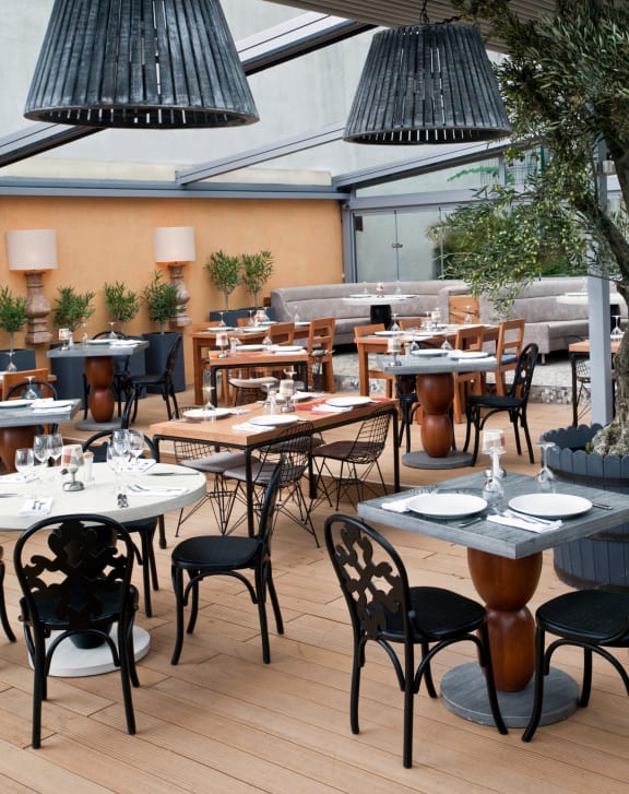 a restaurant patio with white tables and black chairs