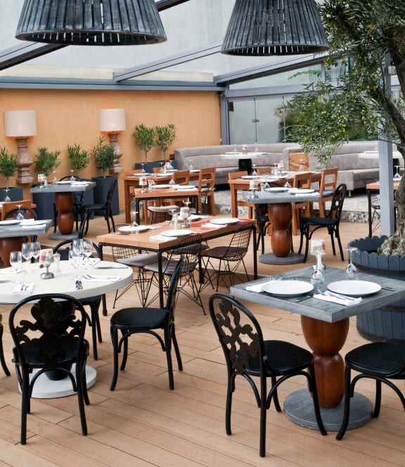 a restaurant patio with white tables and black chairs