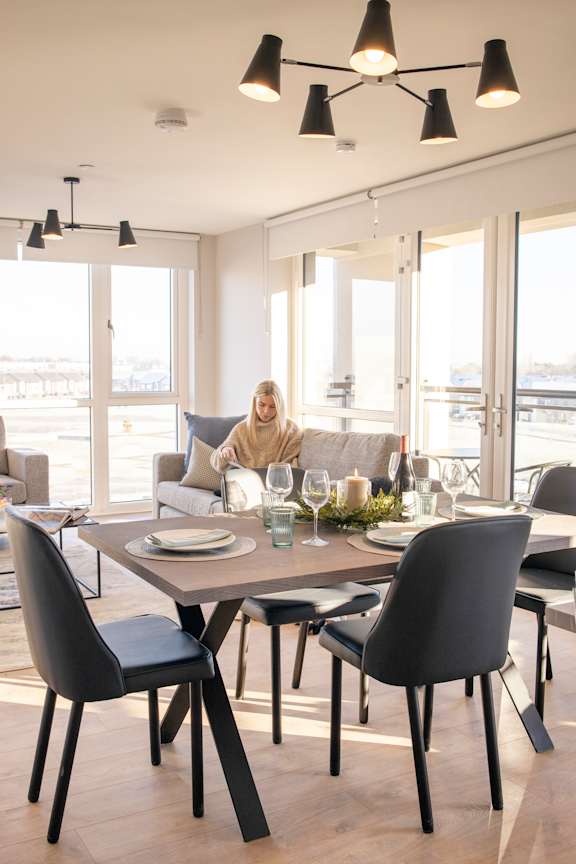 a woman sitting on a couch in a living room with a dining table