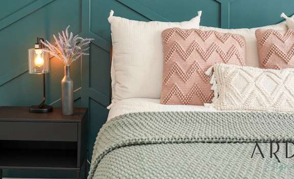 a bed with pillows and a nightstand with a lamp