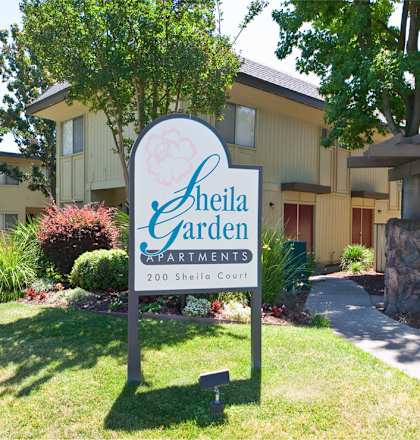 A sign for Sheila Garden in front of a building.