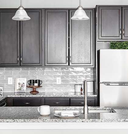 a kitchen with black cabinets and a counter with three black stools