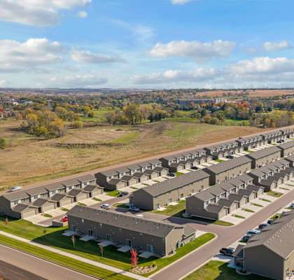 A large housing complex with multiple buildings and a green lawn in the foreground.