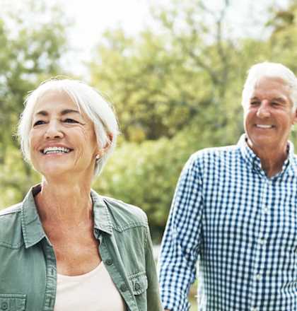 an older man and woman walking in the park