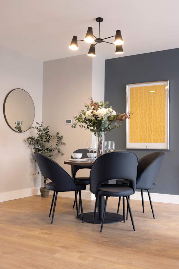 a dining room with a table and chairs and a vase of flowers
