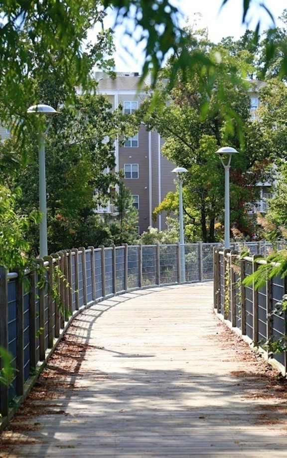 A walkway with a metal fence and street lamps on both sides.