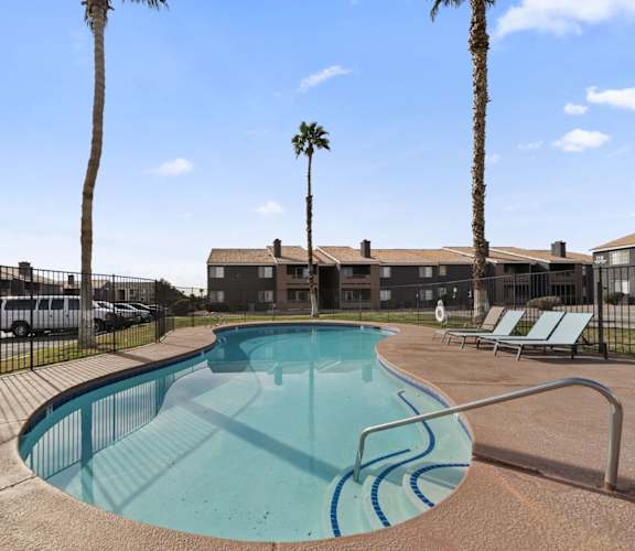 A swimming pool surrounded by palm trees and lounge chairs.