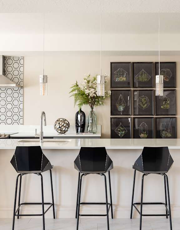 A kitchen with a white counter top and black bar stools.