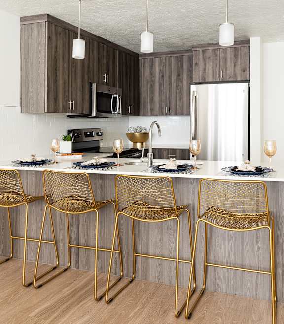 A modern kitchen with a bar area and chairs.