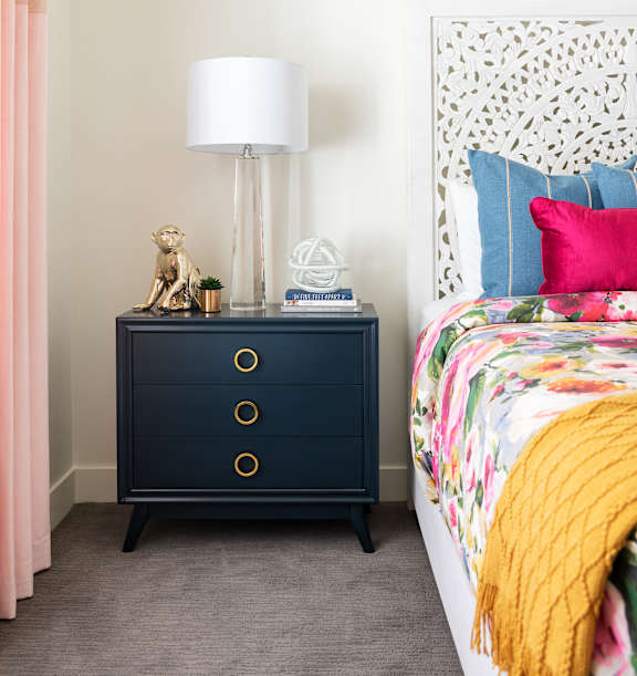 A bedroom with a bed, a nightstand with a lamp, and a curtain.