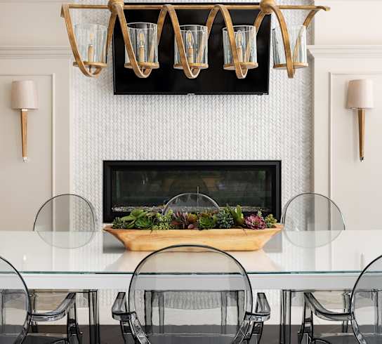 A modern dining room with a glass table and black chairs.