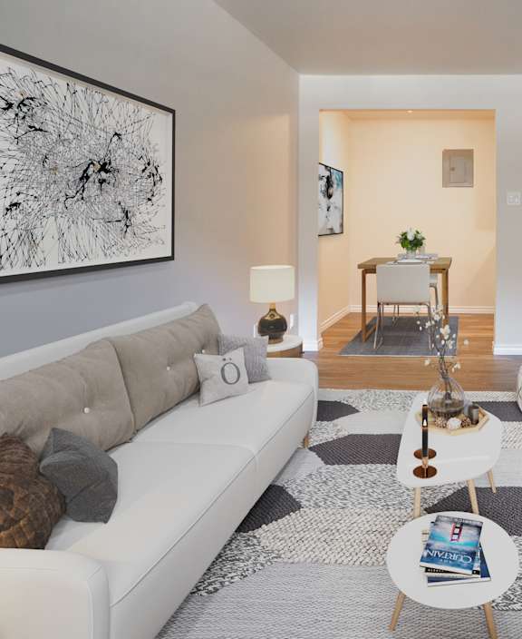 A living room with a white couch and a dining table.