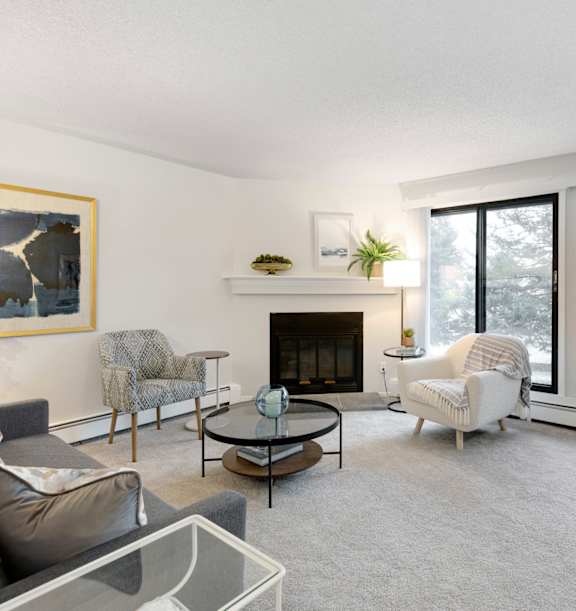 A living room with a grey couch, a fireplace, and a painting on the wall.