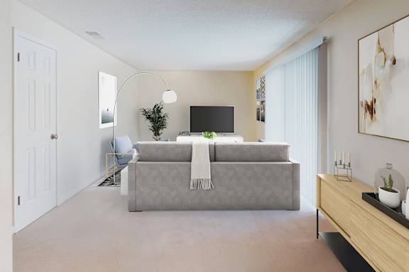 A person is sitting on a chair in a room with a grey couch and a television.
