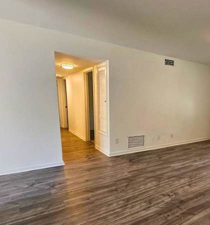 the living room of an empty house with wood flooring and a window