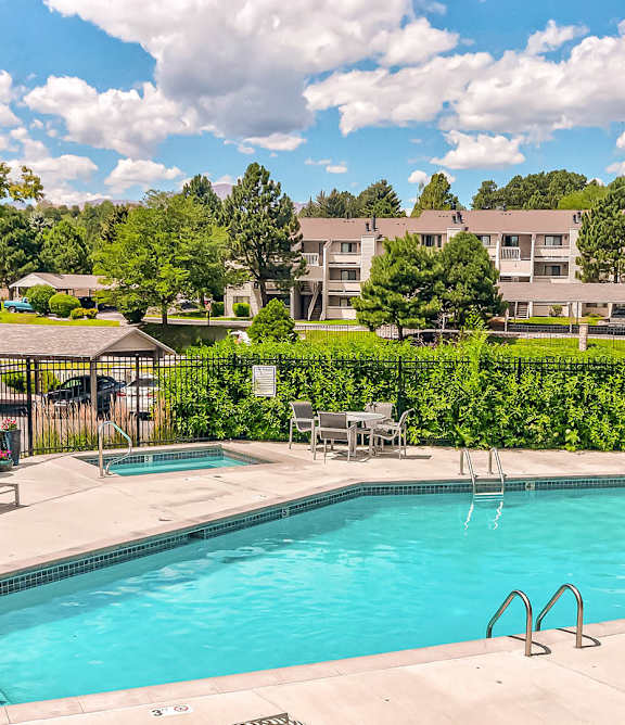 A large swimming pool surrounded by lounge chairs and trees.