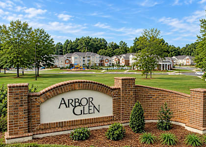A sign that says Arbor Glen in front of a grassy area.