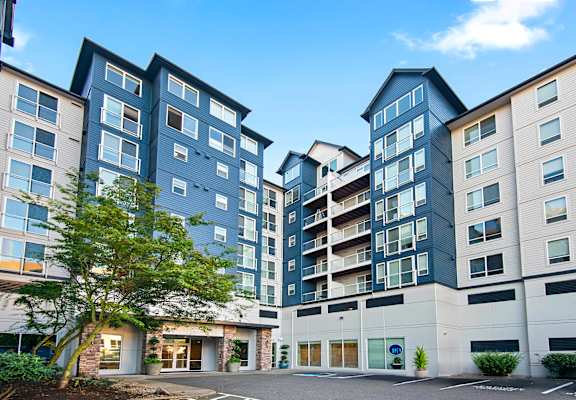 an exterior view of an apartment building with a tree in the courtyard