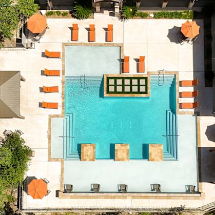 An aerial view of a pool surrounded by orange chairs and green plants.