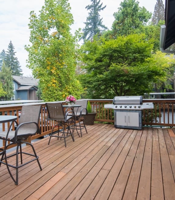 Stillwater clubhouse deck with a grill, tables, and chairs