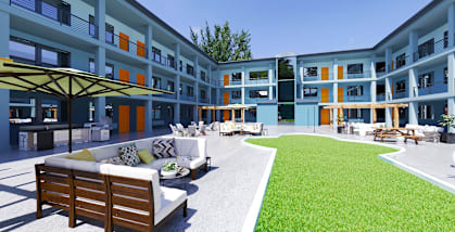 a grassy courtyard with a couch and chairs in front of a building