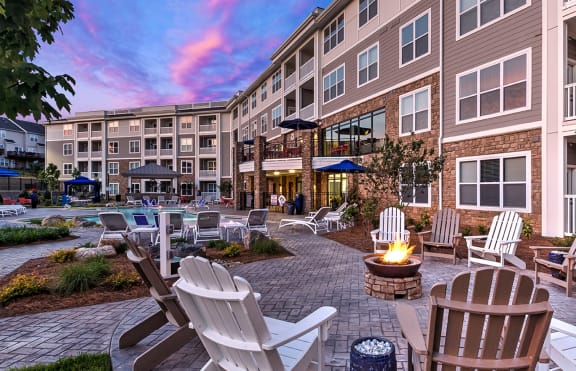 an outdoor patio with a fire pit and rocking chairs at Residence at Tailrace Marina, Mount Holly, NC