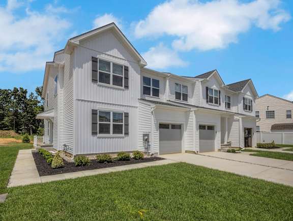 A large white house with a grey roof and a garage.