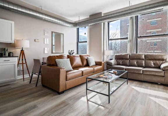 a living room with leather couches and a glass coffee table