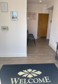 a hallway with a welcome mat and a door in the background