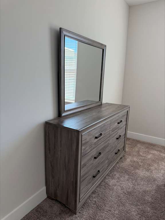 A grey TV stand with a mirror on top and drawers underneath.