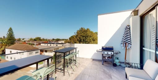 a rooftop terrace with a barbecue grill and tables