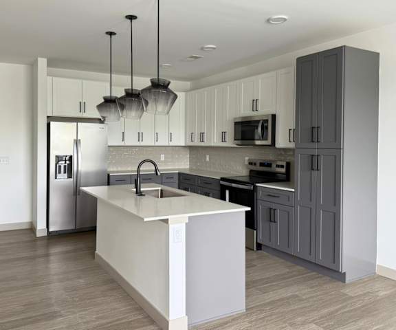 A modern kitchen with a white island and dark wood floors.