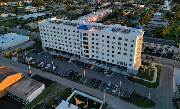 A large white hotel with a parking lot in front.
