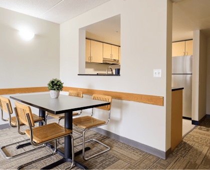 a dining room with a table and chairs      and a kitchen