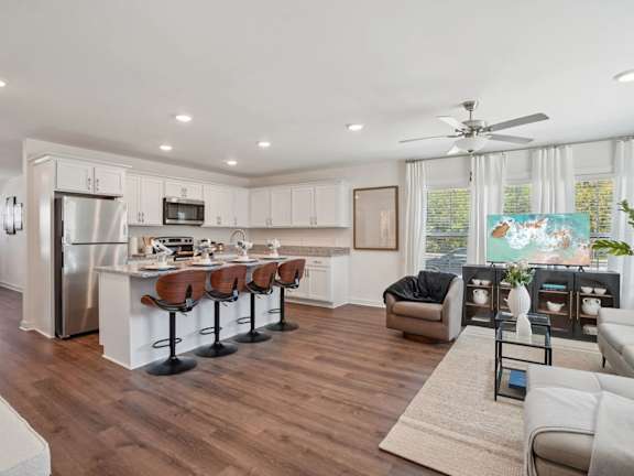 A modern kitchen with white cabinets and a wooden floor.