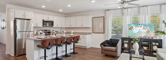 A modern kitchen with white cabinets and a wooden floor.