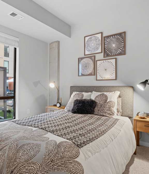 A bedroom with a large bed and a window overlooking a balcony.