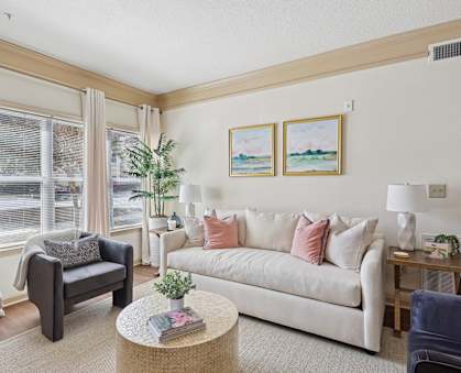 Sunlit living room with cozy seating and modern design at Tattersall Village Apartments near Fort Stewart
