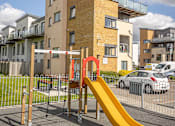 Thumbnail 7 of 7 - a playground with a yellow slide in front of an apartment building