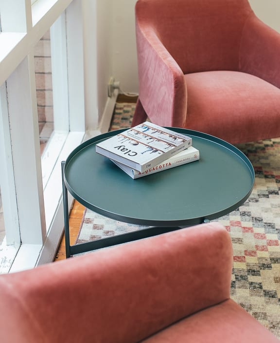 A red chair sits next to a table with a magazine on it.at The Mobile Lofts, Mobile, AL, 36604