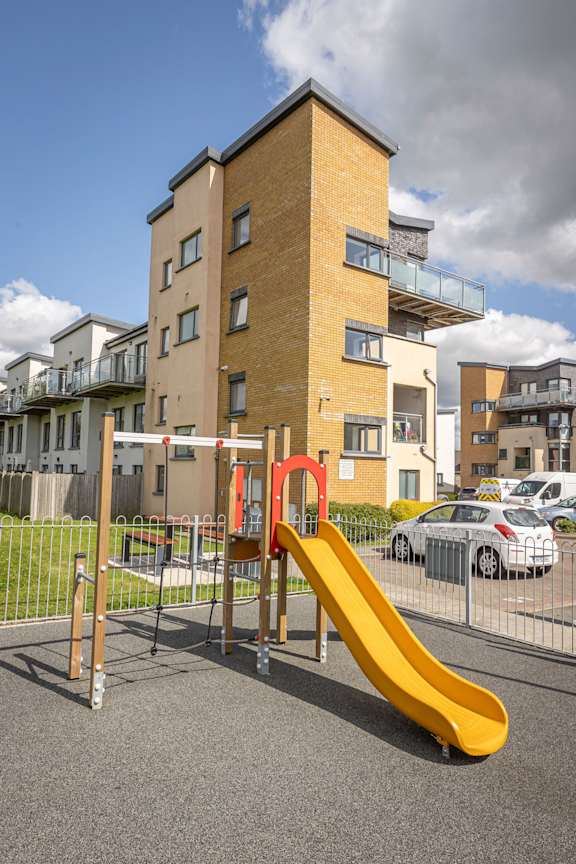 a playground with a yellow slide in front of an apartment building
