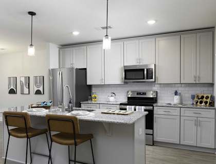 A modern kitchen with a white countertop and grey cabinets.