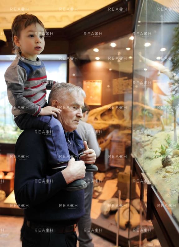 an elderly man holding a child in a museum