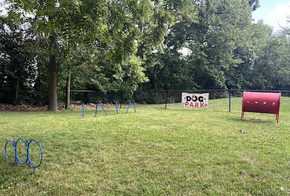 a dog park with a red chair and a sign in the grass