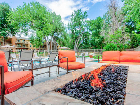 A patio with red chairs and a fire pit.