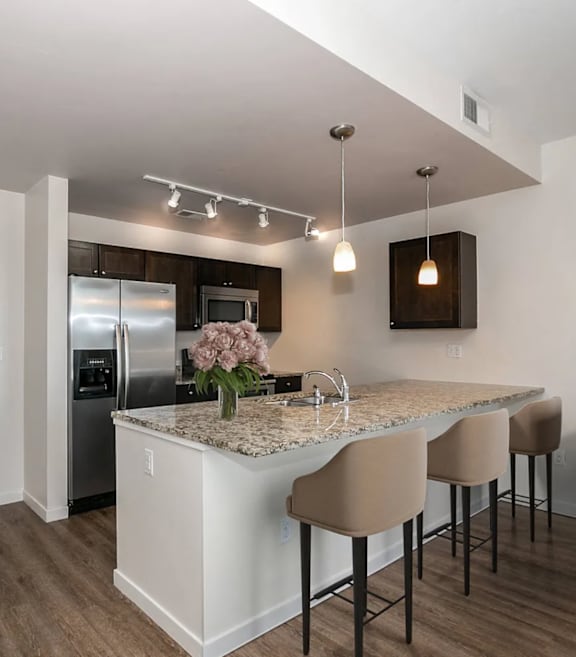 A kitchen with a white island and brown chairs.