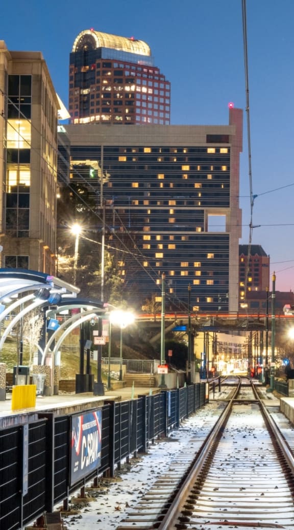 a train station with a city in the background at night  at Link Apartments® Mint Street, Charlotte, North Carolina