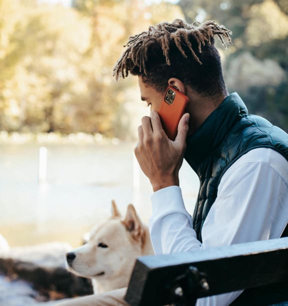 a man talking on a cell phone next to a dog