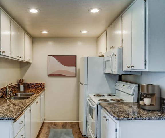 a kitchen with white appliances and granite counter tops